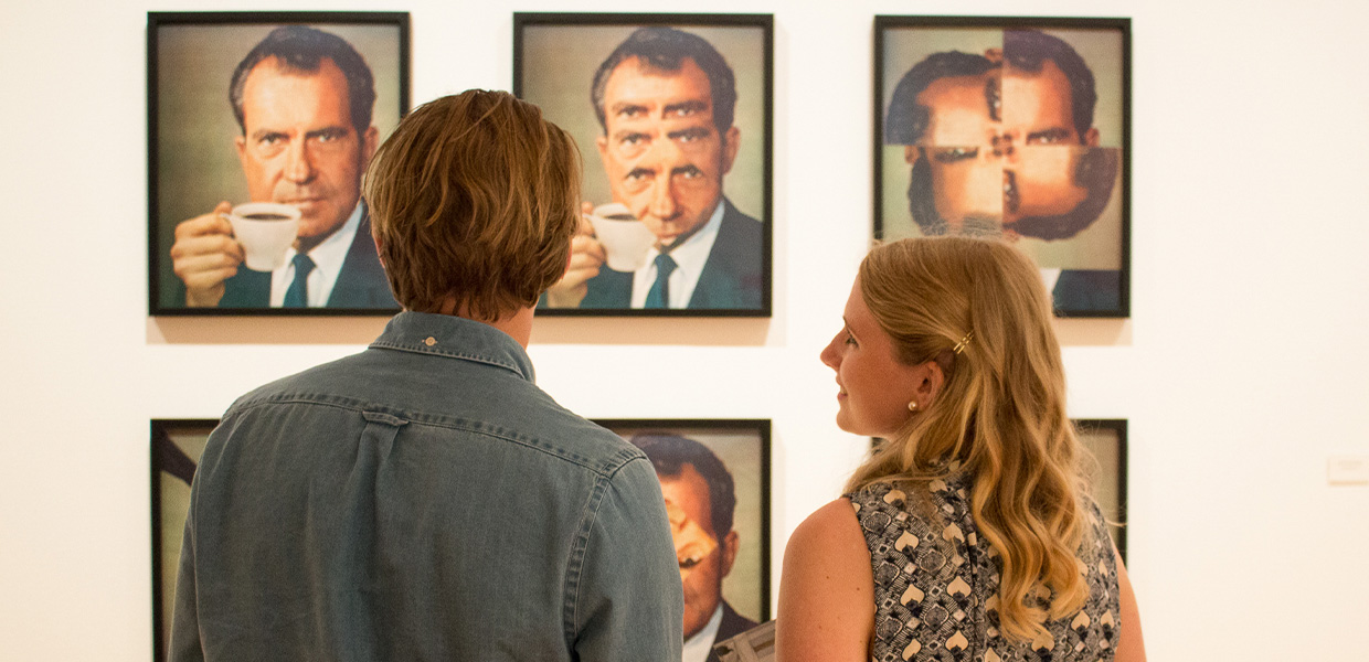 To personer ser på fotografier av en mann med kaffekopp, trolig Richard Nixon. Bildene er montert i et rutenett på veggen i et galleri.