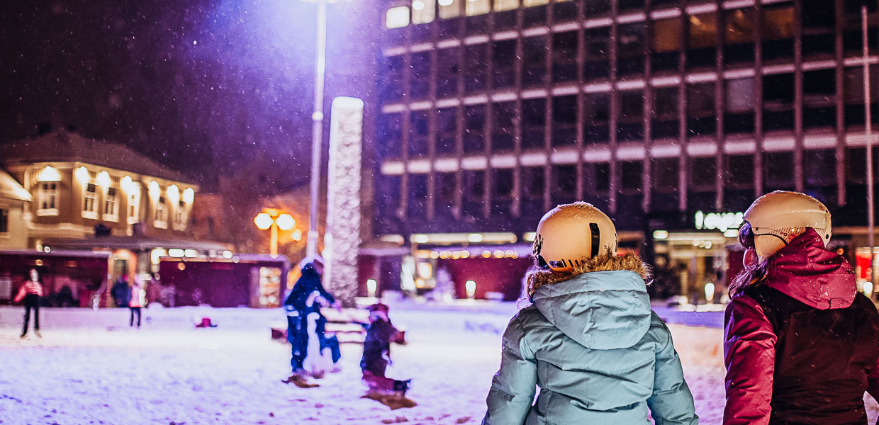 to barn som sitter på en benk ved skøytebanen i larvik torg