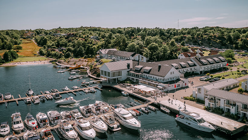 Luftfoto av en marina med luksuriøse båter og Hvite bygninger; Havna Hotel på Tjøme.