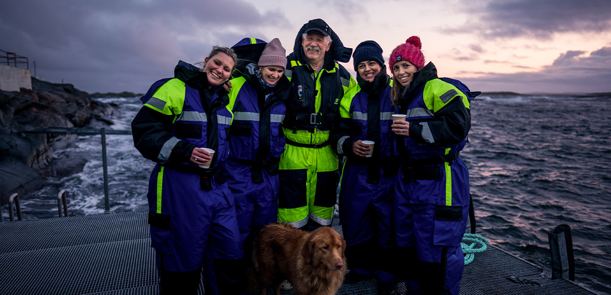 Gruppe med mennesker på brygge ved sjøen