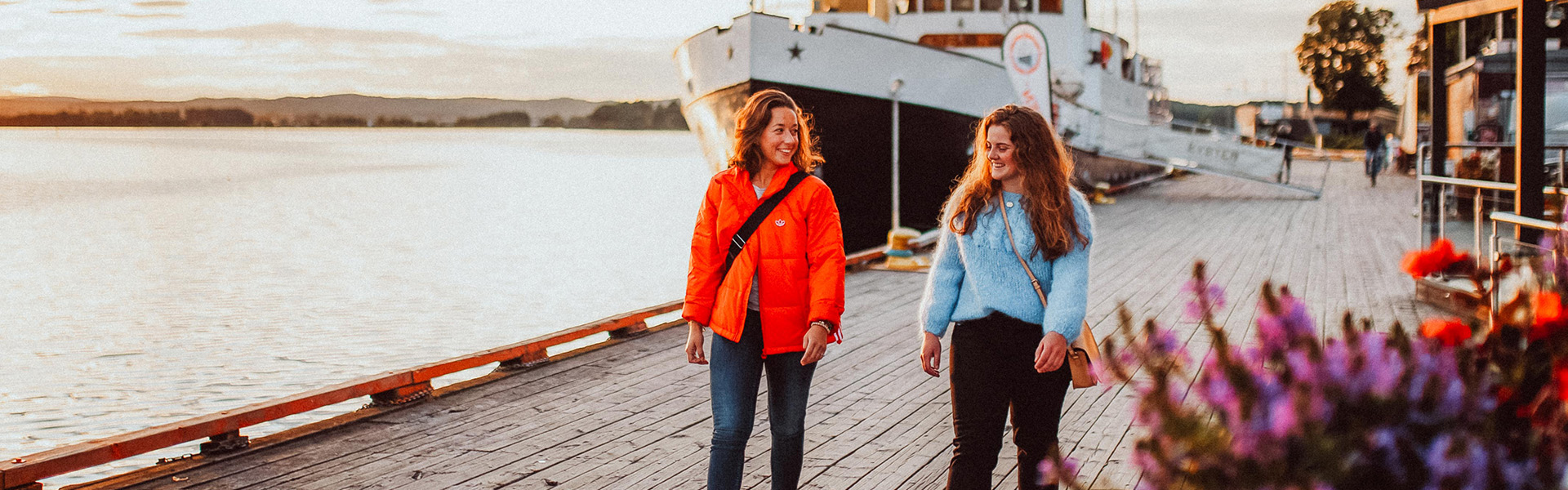 to personer går på brygge med havutsikt