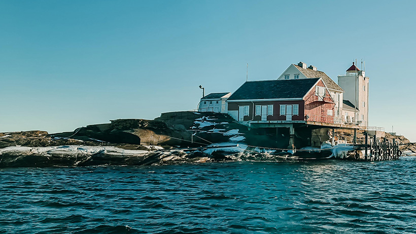 Fulehuk fyr med snø på holmen med sjø rundt